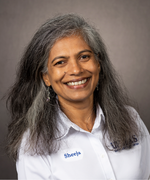 Woman with long curly hair smiles at camera wearing white collared shirt.